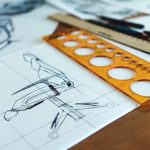 Detailed architectural drawings with design tools on a desk signify creativity and planning.
